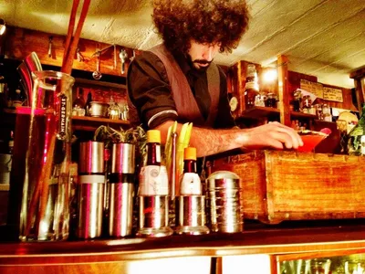 A bartender garnishing a cocktail behind the bar
