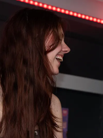 A guest laughing under the red LED strip in the bar